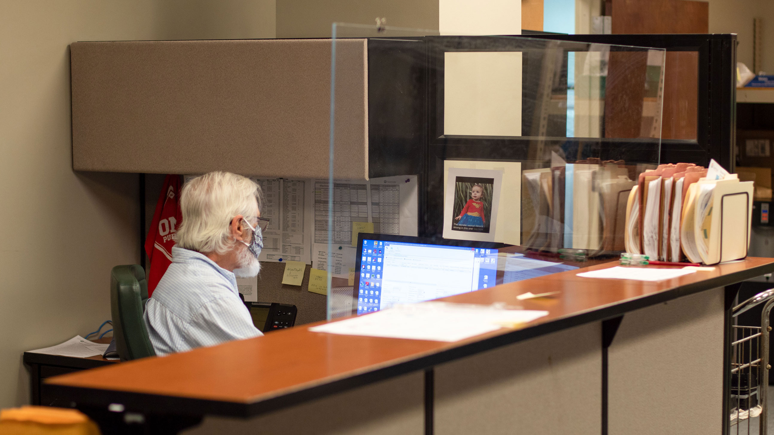 Older man sitting at a desk with a barrier around it