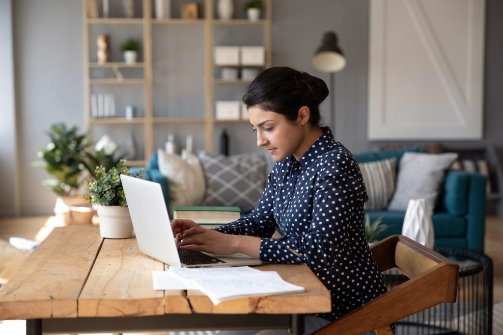 Woman working from home on a large wooden desk.
